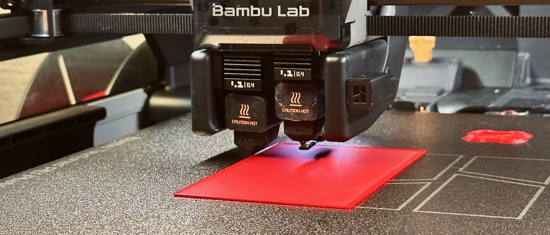 Bambu Lab H2D dual nozzle laying down a red first layer