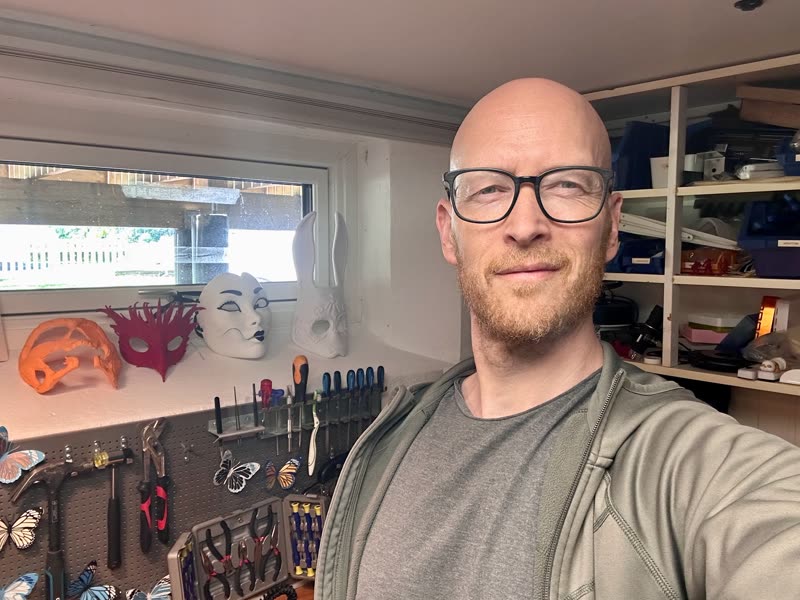 Trond at the workbench, printed masks on the shelf behind