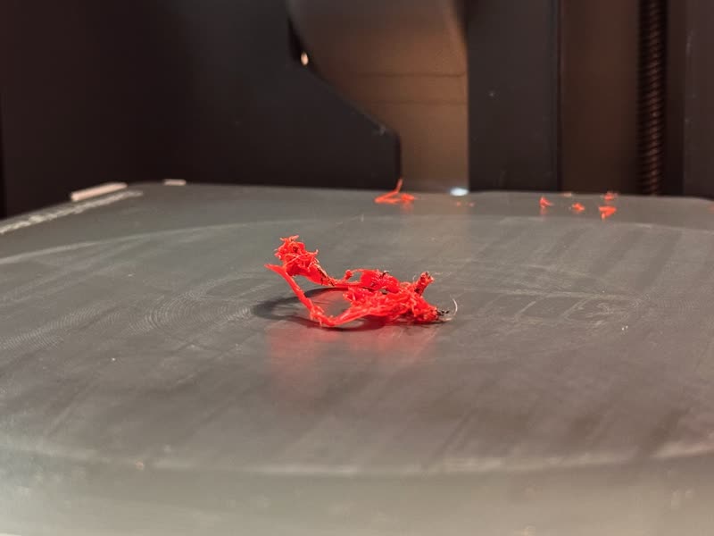 A failed print — red filament spaghetti on the build plate