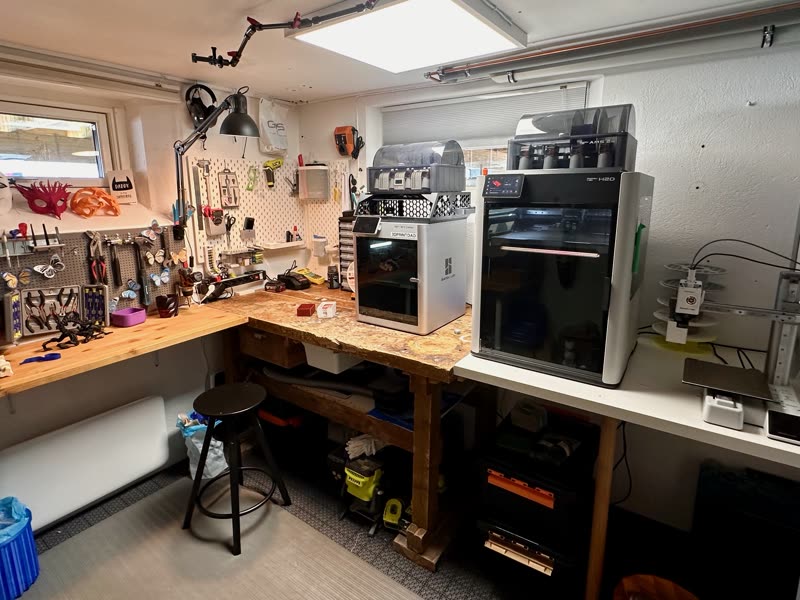 The workbench: three Bambu Lab printers, pegboard tools, and printed projects